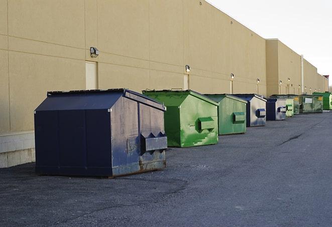 a construction worker unloading debris into a blue dumpster in Berea